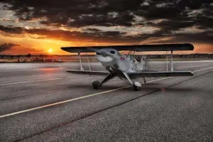 Fixed-wing biplane on a runway at sunset